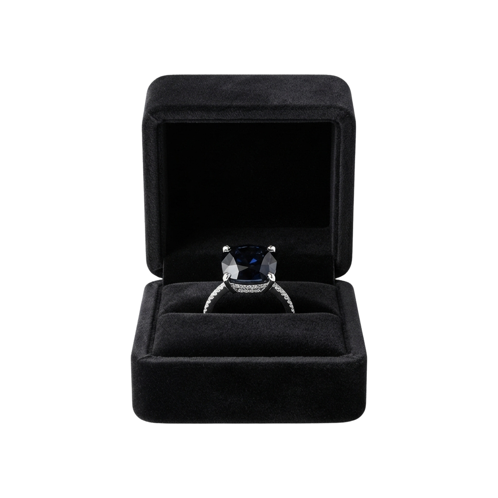 A black gemstone ring set in a pronged band displayed in an open black velvet ring box