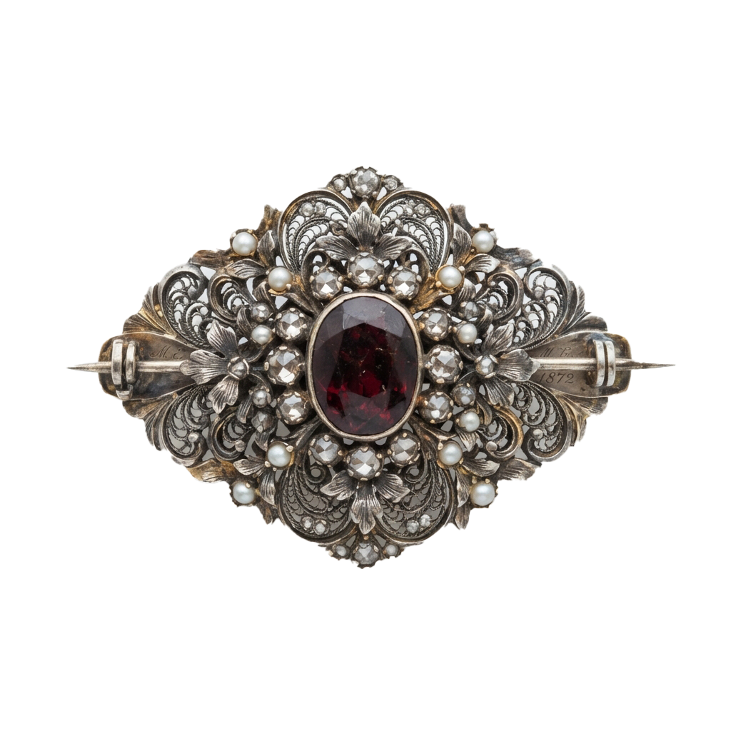 An antique brooch featuring a central garnet stone surrounded by ornate metal filigree and small pearls, with decorative pinbacks on each side