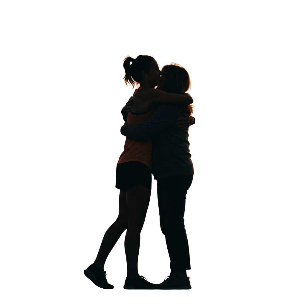 Two people embracing closely against a dark background with warm lighting.
