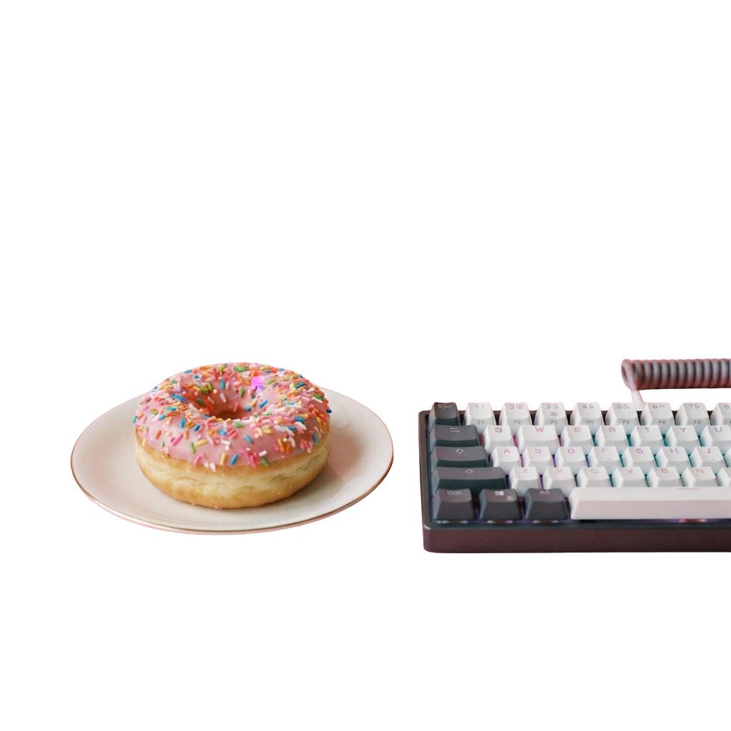 A colorful sprinkled donut on a white plate beside a mechanical keyboard