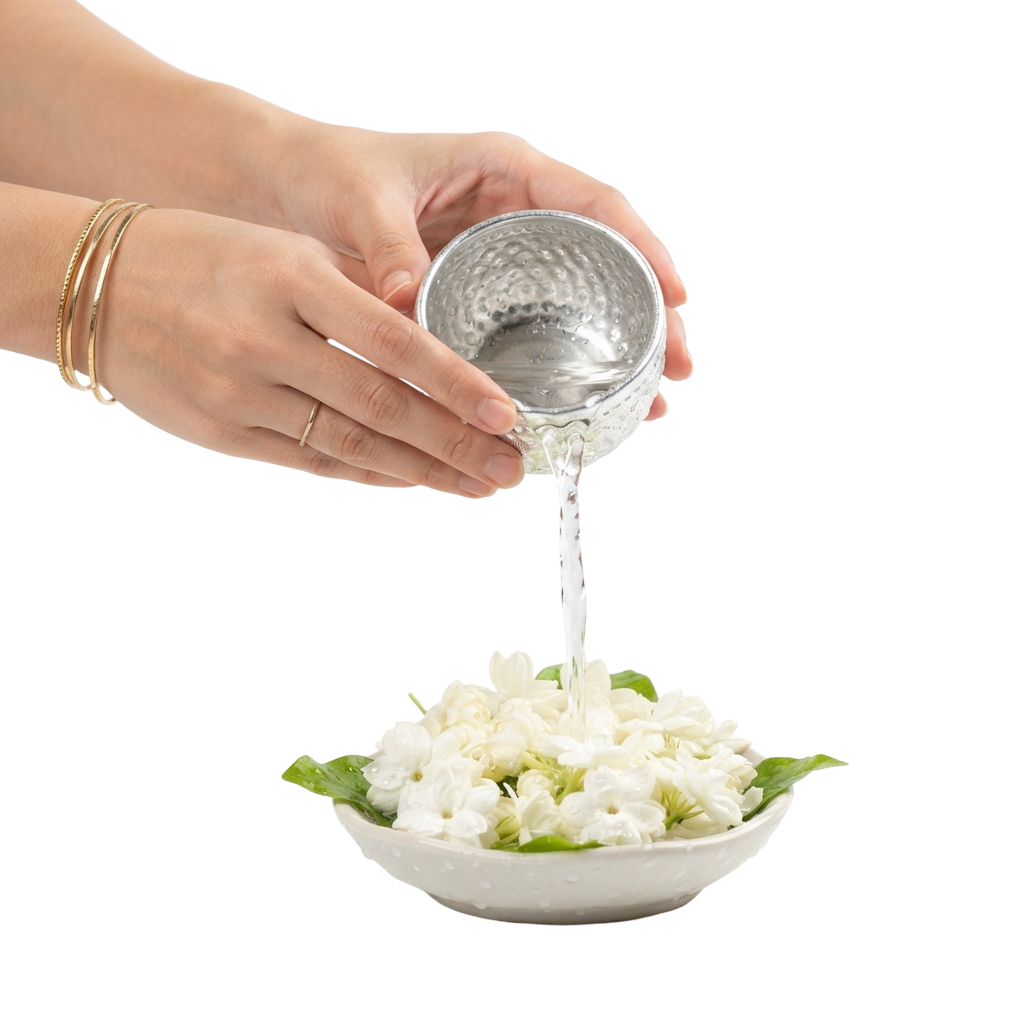 Hands pouring sauce from a small container onto a plate of white flower-shaped vegetables.