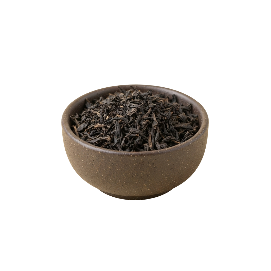A ceramic bowl filled with dark, loose leaf black tea against a plain background