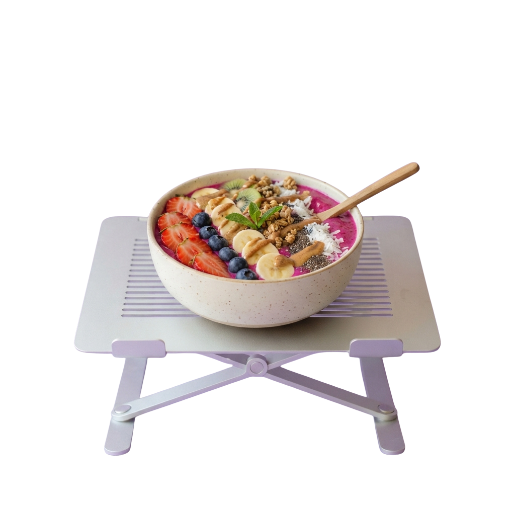 A white bowl filled with acai mixture topped with berries, banana slices, granola, and chia seeds on a purple tray