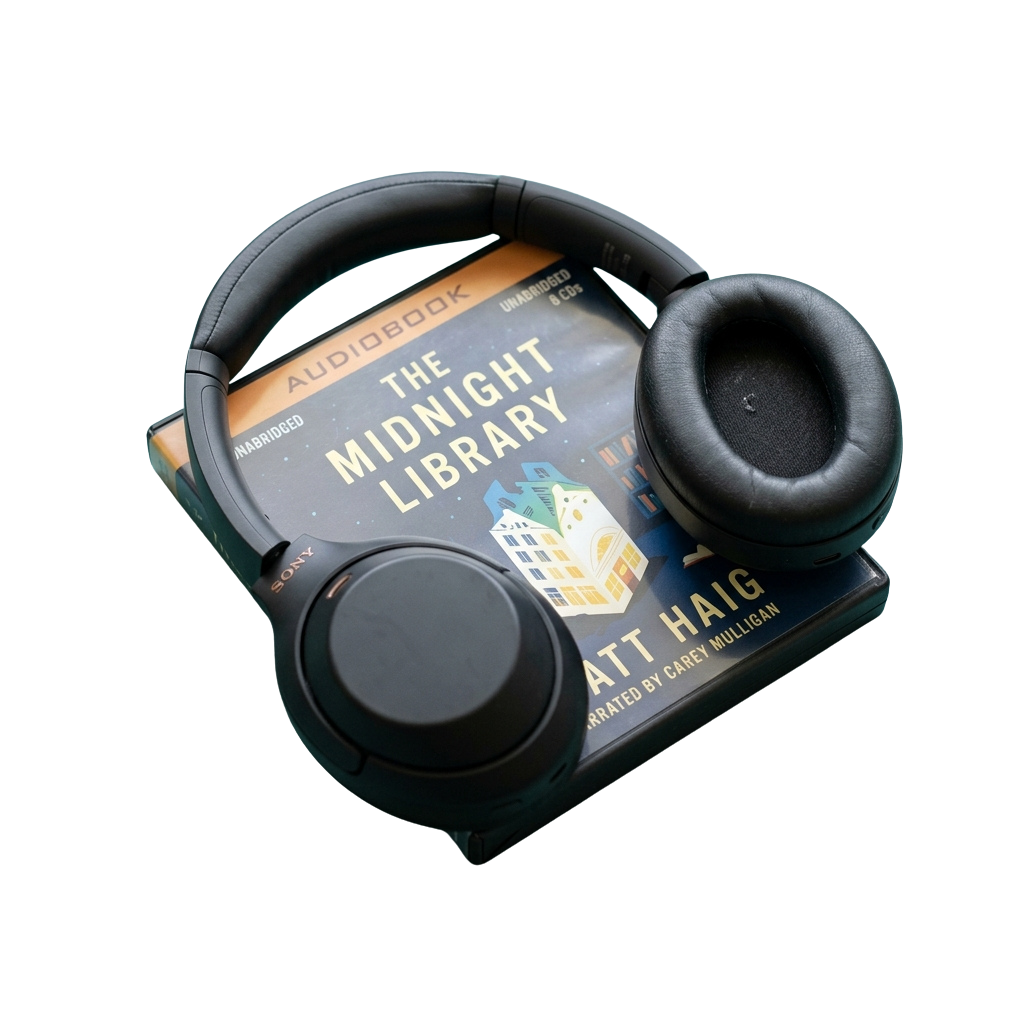 Black headphones resting on an audiobook cover titled The Midnight Library by an author.