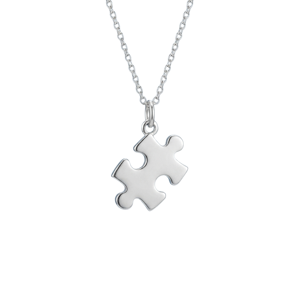 A silver-colored puzzle piece pendant on a delicate chain against a dark background