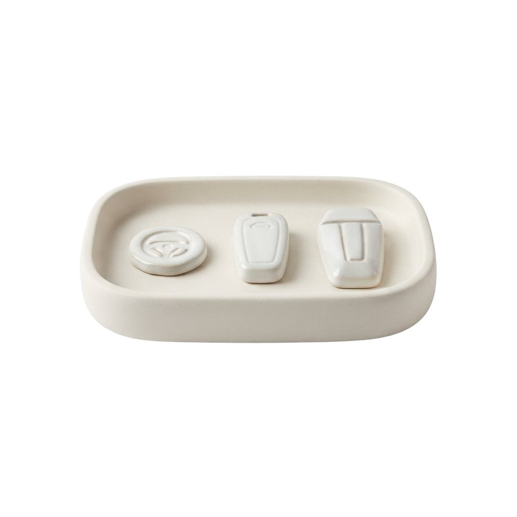 A white rectangular tray holding three white remote control buttons and one circular button.