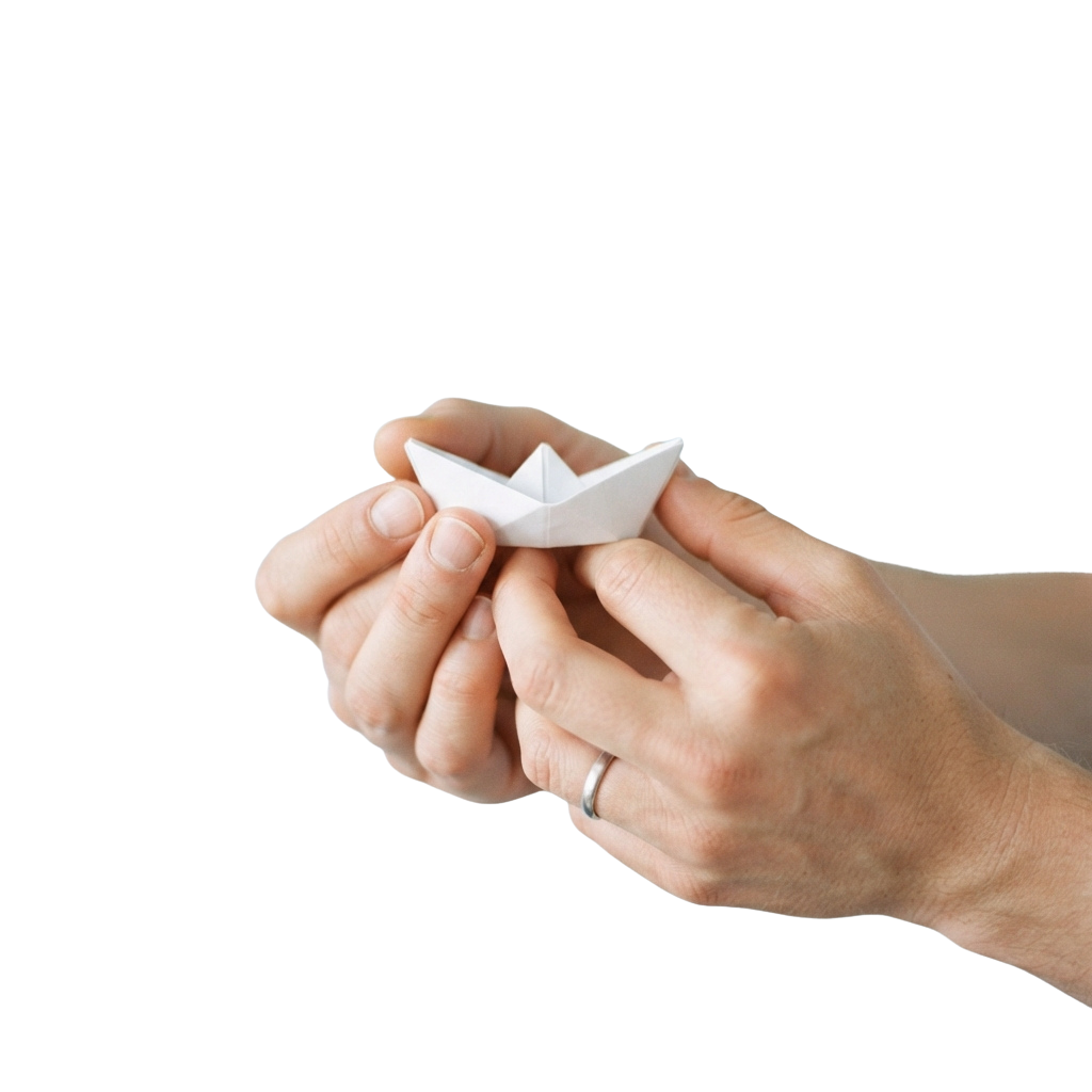 Two hands holding a small white origami boat against a black background