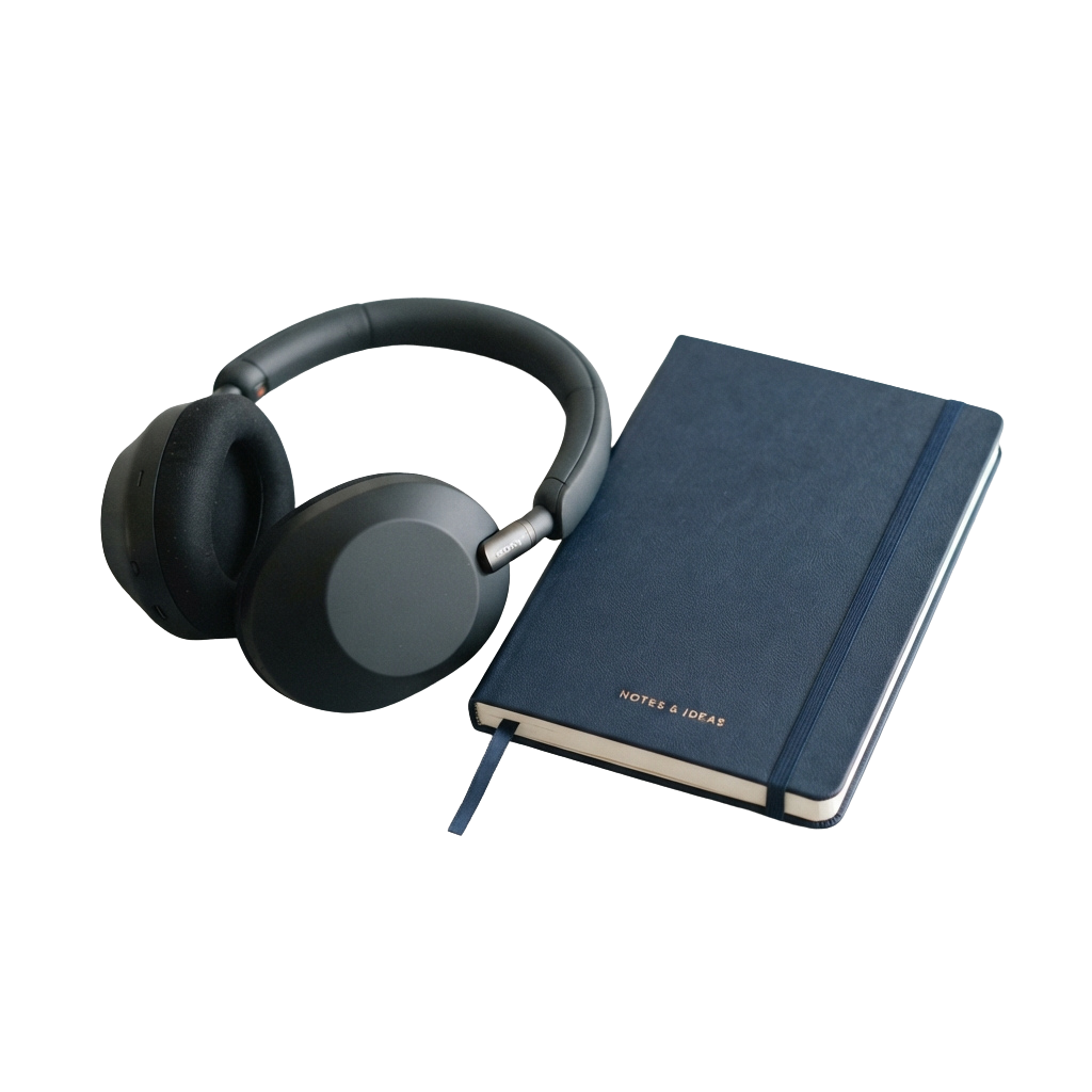 Dark blue over-ear headphones placed next to a matching dark blue notebook labeled Notes & Ideas