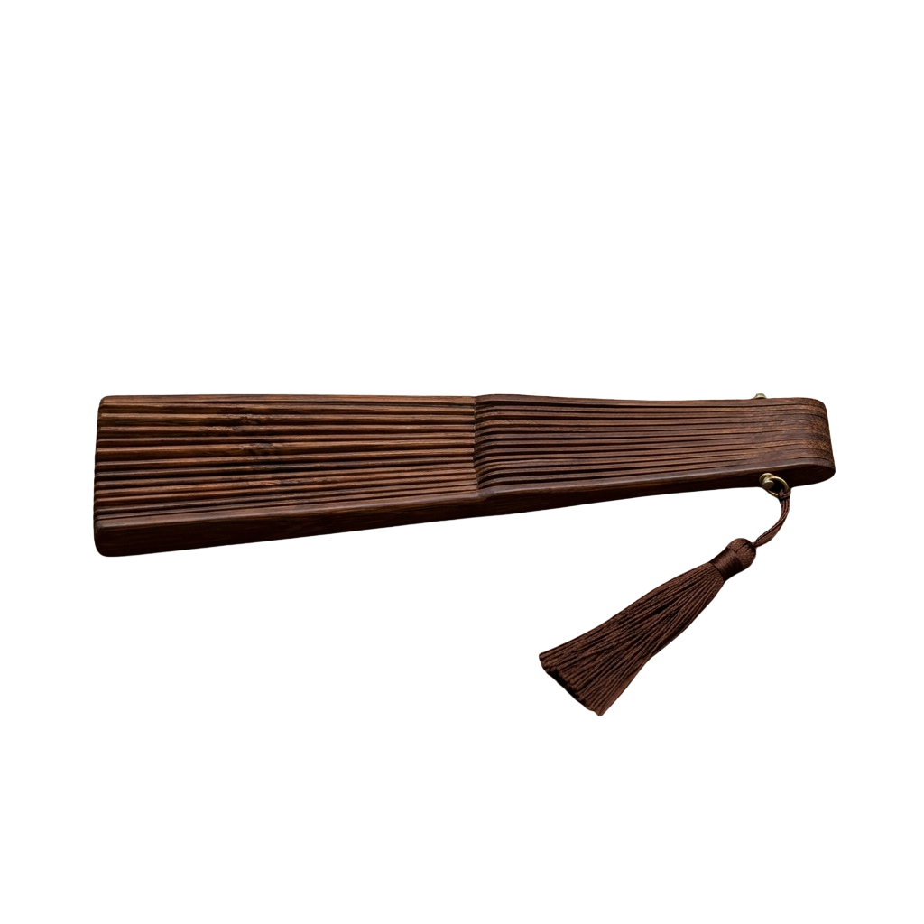 A wooden hairbrush with a tassel hanging from the handle against a dark background