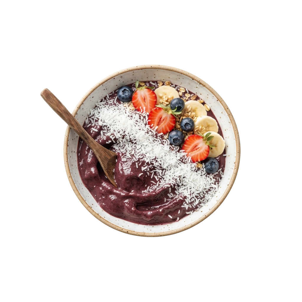A white bowl filled with a dark purple acai mixture topped with coconut flakes, strawberries, blueberries, and banana slices, served with a wooden spoon