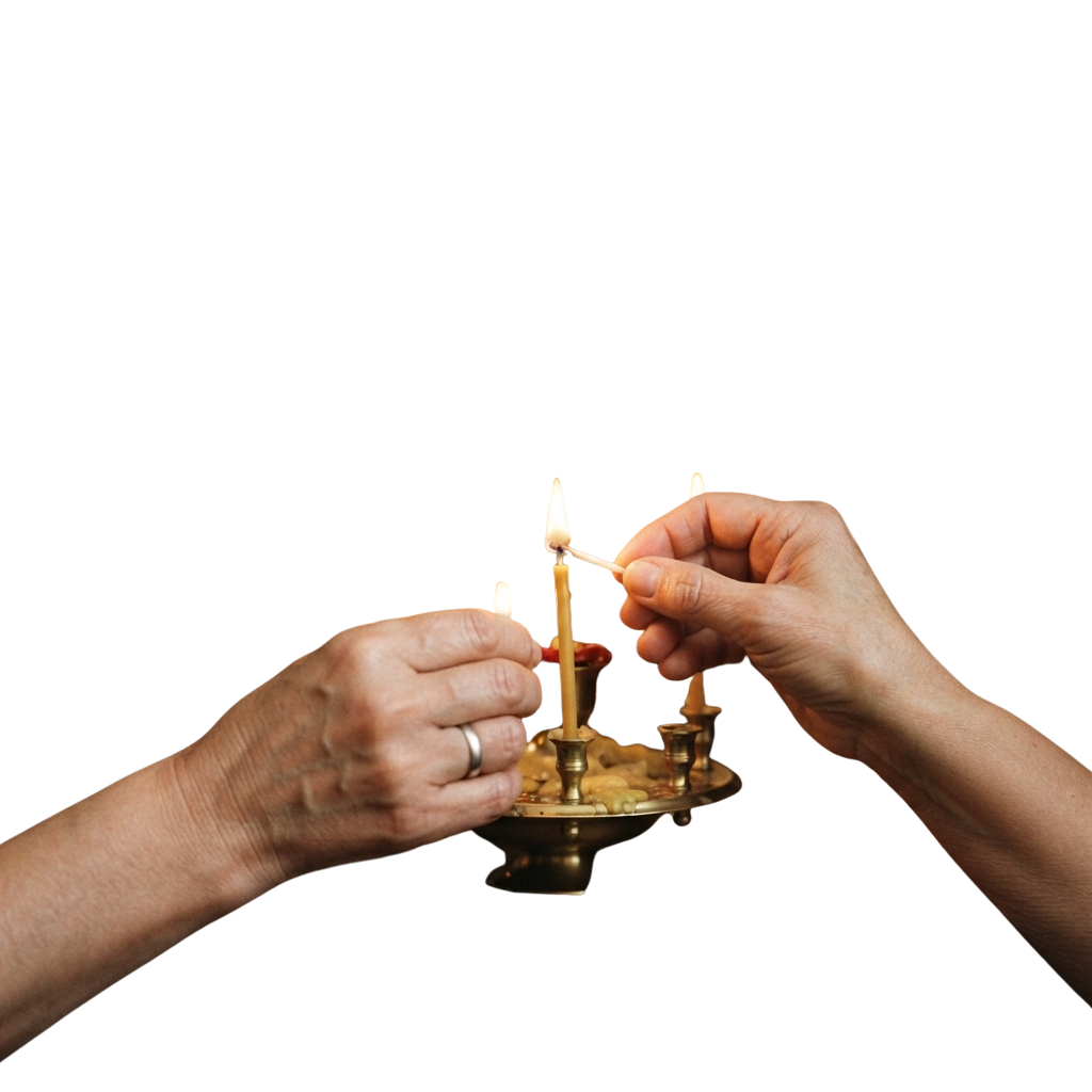 Two hands lighting candles in a brass holder against a dark background