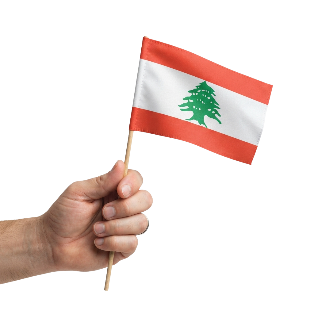 A hand holding a small Lebanese flag with red, white stripes and a green cedar tree emblem