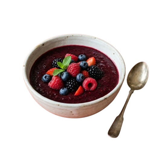 A white ceramic bowl filled with deep red chia pudding topped with fresh raspberries, blueberries, and blackberries alongside a spoon