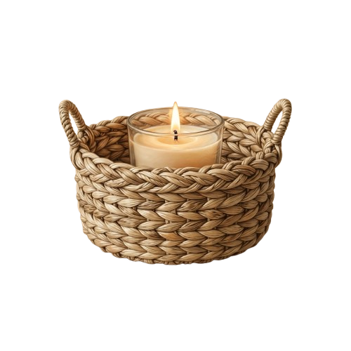 A woven basket candle holder with two handles containing a single lit candle.