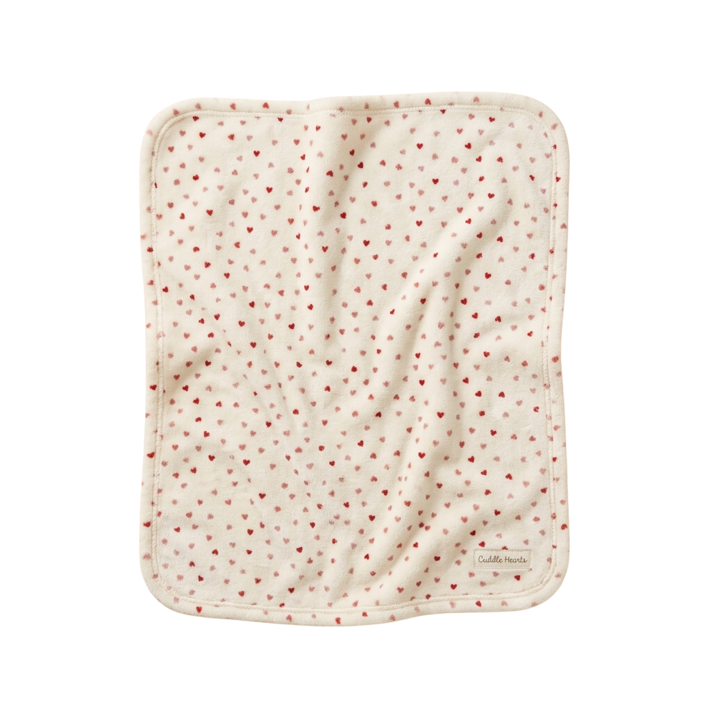 A light-colored baby bib with small red heart shapes scattered across the fabric