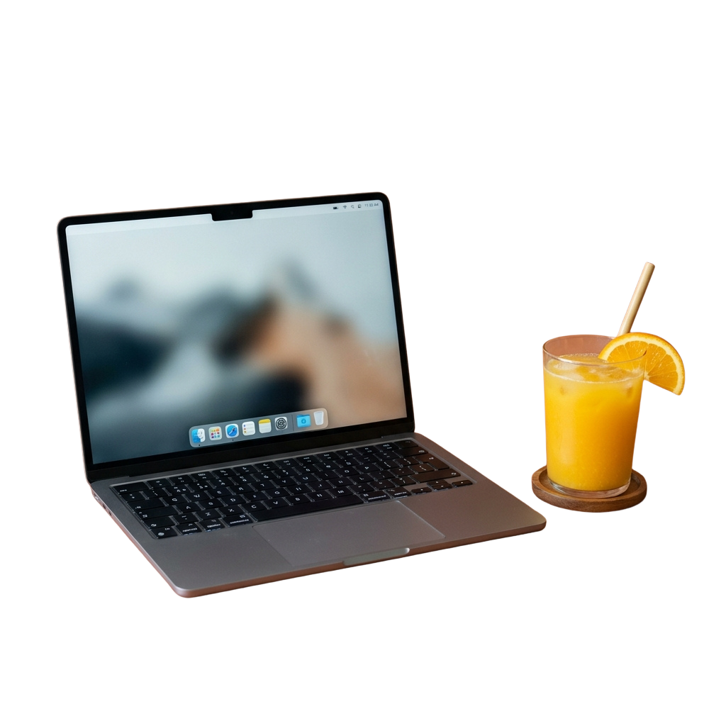 A laptop displaying a desktop screen next to a glass of orange juice with a slice on the rim