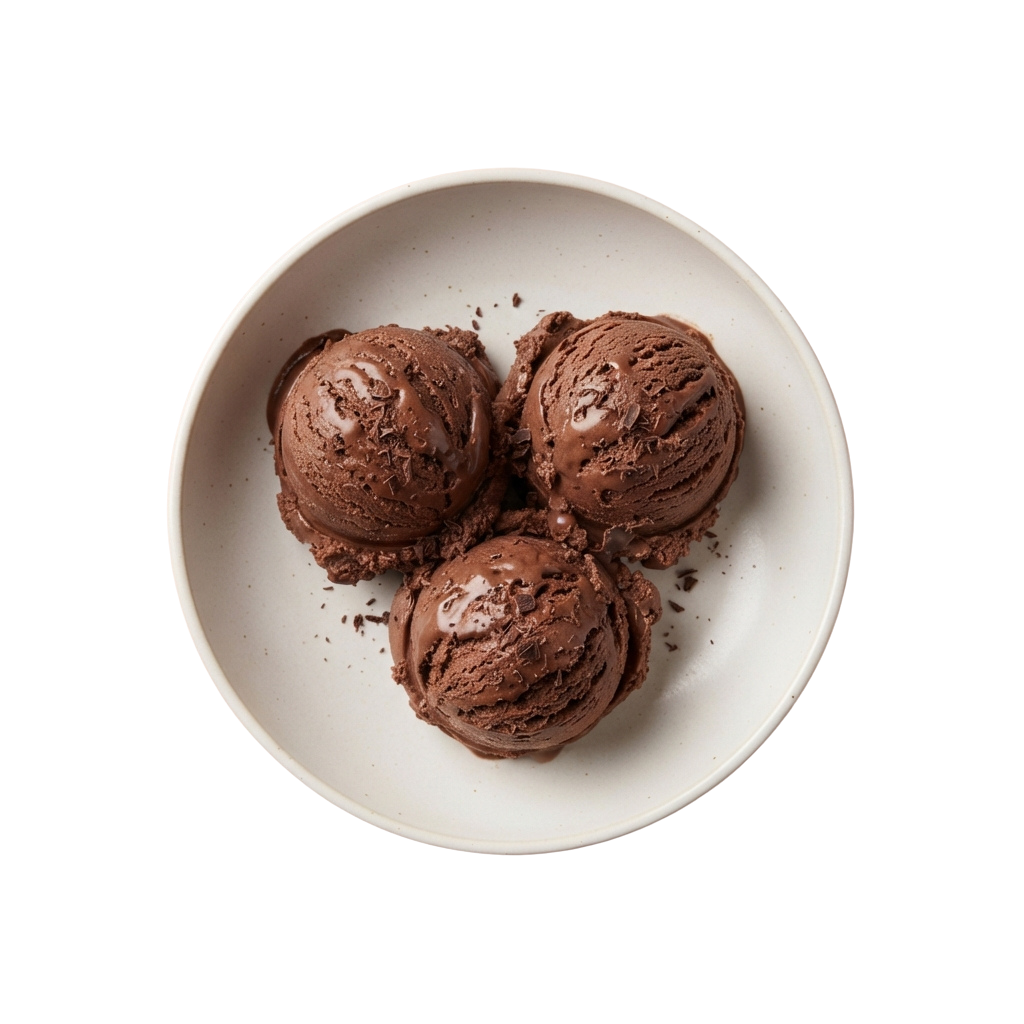 Three rich chocolate ice cream scoops in a white bowl with chocolate shavings around them