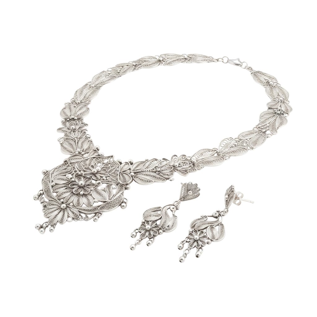 Silver filigree necklace with ornate pendant and matching pair of dangling earrings on black background