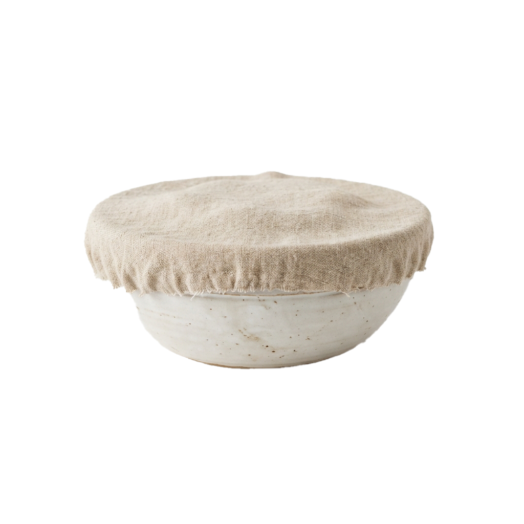 A light-colored ceramic bowl with a beige linen cover placed on top