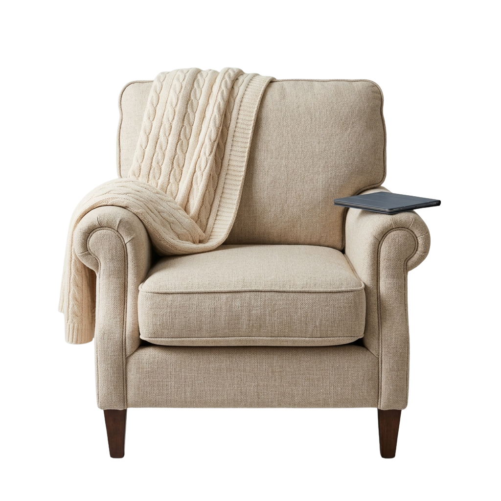 A light beige armchair with rolled arms, draped with a cream cable knit throw, and a small side table holding a tablet.