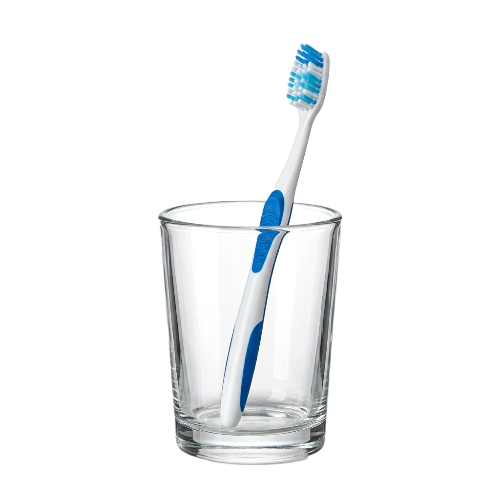 A toothbrush with blue bristles standing upright in a clear glass cup