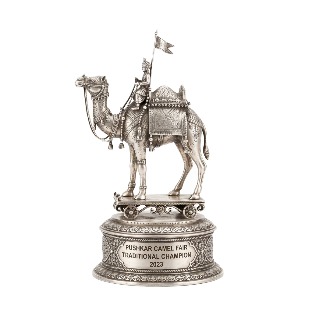 A silver trophy featuring a rider on a camel with a flag, labeled Pushkar Camel Fair Traditional Champion 2023