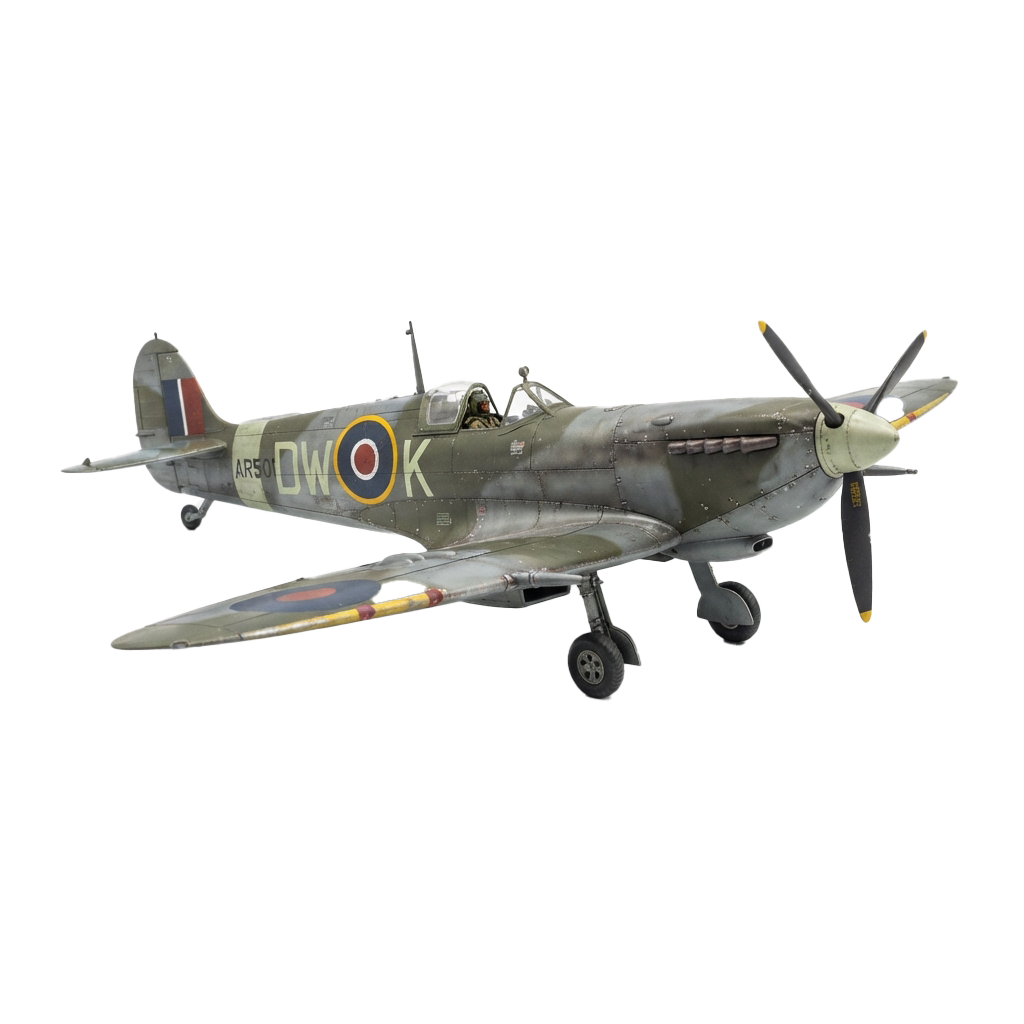 A green and grey military Spitfire plane flying with roundels and markings on its wings and fuselage