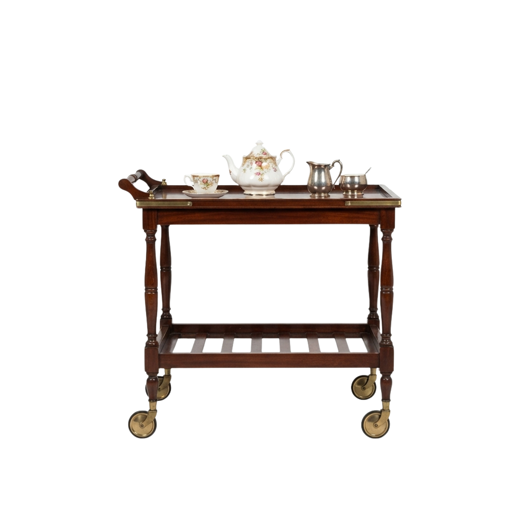A wooden tea cart with a serving tray on top holding a teapot, cups, and a sugar bowl, on four gold-tipped wheels