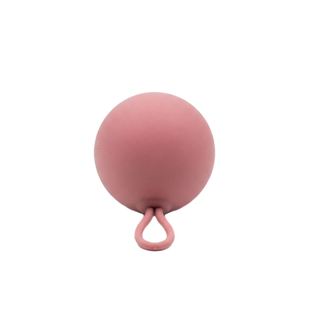 A pink balloon with a twist knot at the end of its tail against a black background
