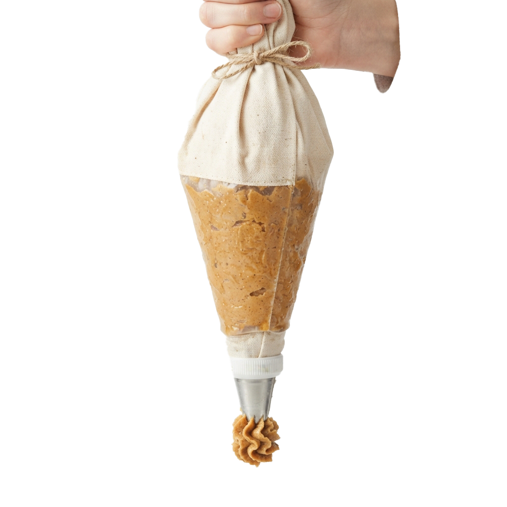 Hand holding a pastry bag filled with brown icing, dispensing a decorative rosette.