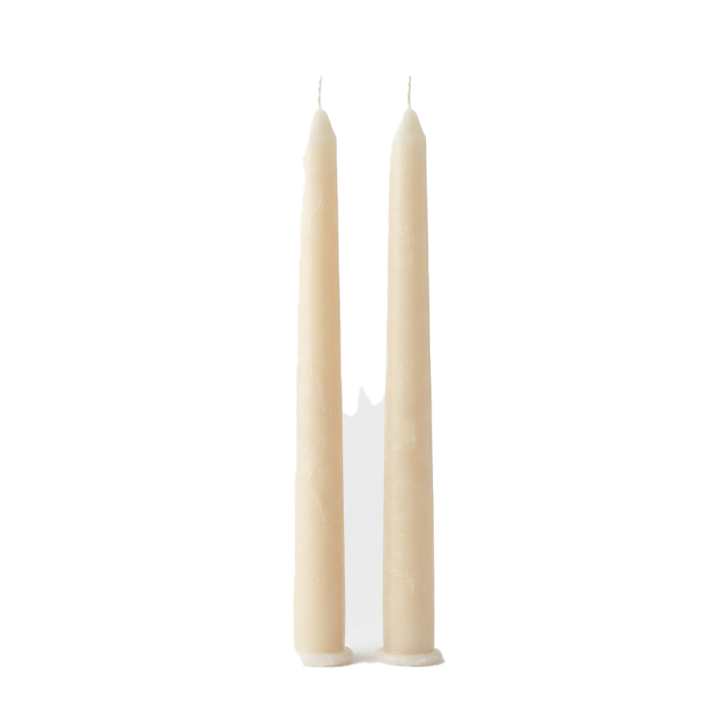 Two tall, unlit white candles standing upright next to each other on a dark background