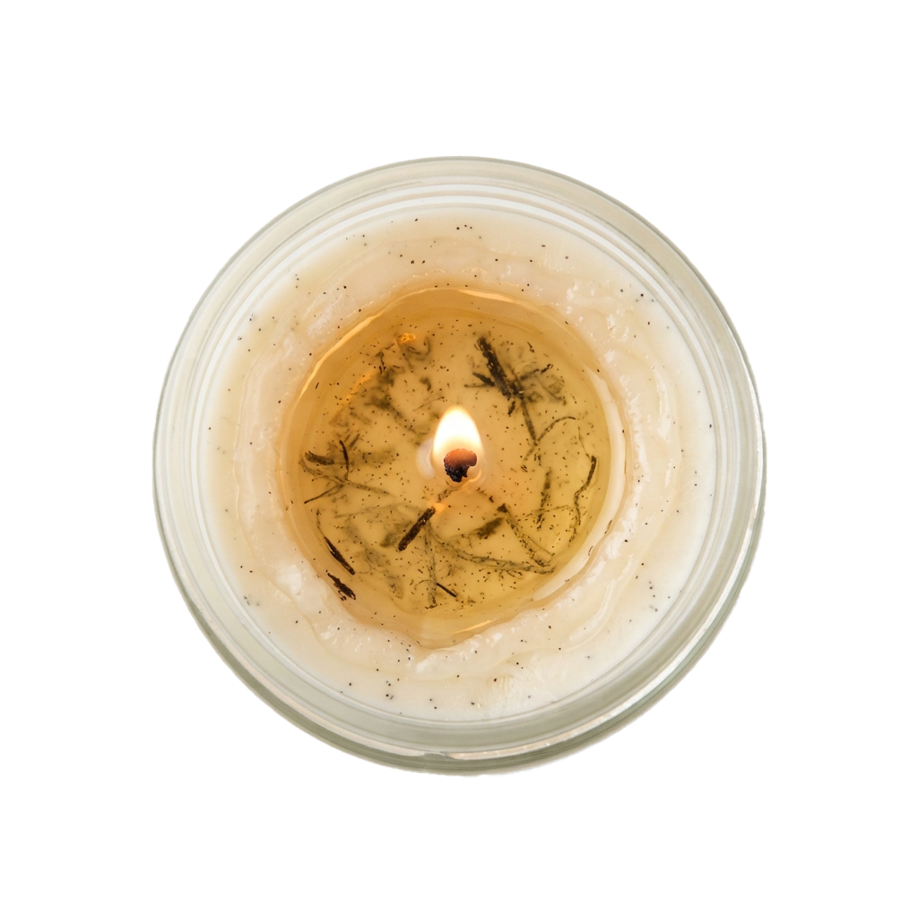 A lit candle with dried herbs and small glittery specks inside a transparent glass container